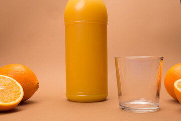orange juice, close-up of a bottle of freshly squeezed orange juice and a glass cup, on the sides you can see the oranges cut in half