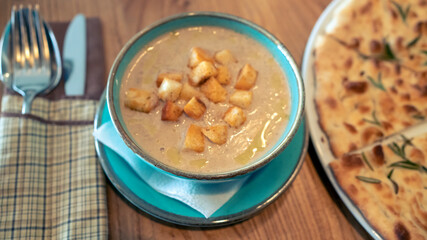 Bowl of mushroom soup with croutons on rustic wooden background