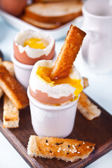 boiled egg in eggcup on wooden board with crispy toast.