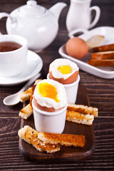 boiled egg in eggcup on wooden board with crispy toast.