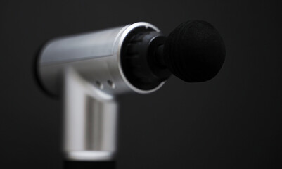 Massage percussion device on black background. Suitable for advertising.