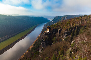 Aerial panorama view of Elbe River and sandstone mountains in Saxon Switzerland National Park near Stadt Wehlen on a sunny winter day with blue sky cloud, Saxony, Germany