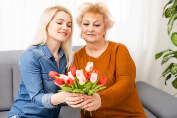 child daughter congratulates mother and gives a bouquet of flowers tulips