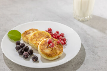 homemade cheesecakes with black and red currants and a glass of milk on a concrete background