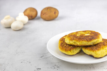 fried lean potato pies with mushroom filling, potatoes and mushrooms on a concrete background