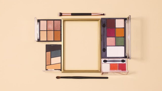 Make up products appear around golden frame for copy space on beige background. Stop motion