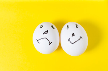 Fototapeta premium Eggs with funny and sad emotional faces, on a yellow background.