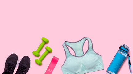 Banner. Sports blue water bottle, two green dumbbells, black sports sneakers, pink elastic band for fitness and a turquoise short top isolated on pink background. Healthy lifestyle. Sport equipment