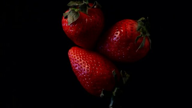 Sweet Ripe Strawberries rotating on a dark background.