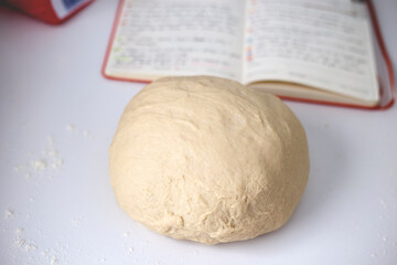 Massa de pão fresca em cima da bancada com livro de recetias 