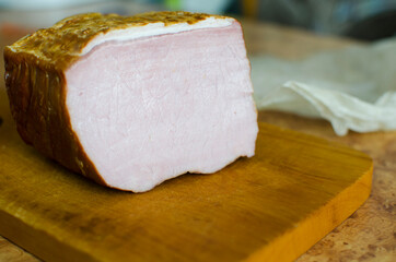 Smoked pork in a cut lies on a wooden cutting board