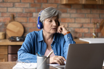 Virtual learning for aged people. Active latin female retiree sit by laptop in headset confer with...
