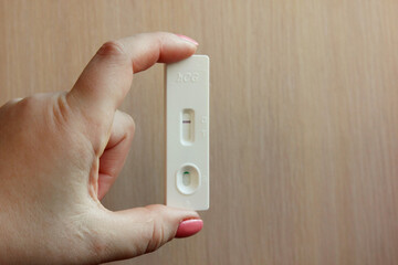 Woman is hand with pink nails, holding a negative pregnancy test on a light background. Motherhood, pregnancy, the concept of birth control. Health problems and problems with conception. Copy space