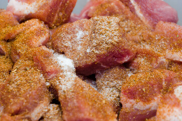 Raw pork chopped into small cubes and seasoned with spices: bell pepper, red pepper, curry, barbecue seasoning, salt..Close-up