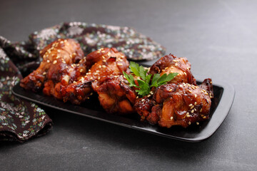 Plate of chicken wings in soy sauce with honey and sesame. Traditional asian recipe. Dark background.