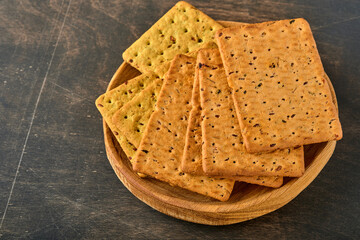 Cracker with flax seeds and oat bran rectangular shape for healthy, dietary and balanced diet on dark wooden background. Snack for proper nutrition.