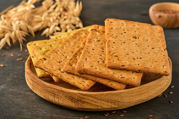 Cracker with flax seeds and oat bran rectangular shape for healthy, dietary and balanced diet on dark wooden background. Snack for proper nutrition.