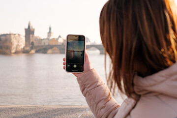 Blogger or influencer recording video from Prague. Vlogger shooting vlog on the mobile phone. Girl makes photo on her smartphone. Travel content
