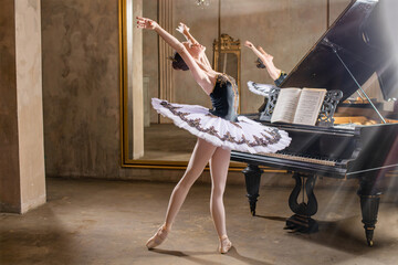 Young ballerina in a white tutu dancing on beautiful old piano in a vintage interior