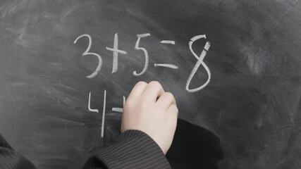 Close-up of male hands in a black suit, the teacher writes math equations on a black chalkboard. School concept - Powered by Adobe