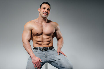 A young athlete in jeans poses sitting in the studio. Sport.