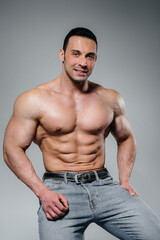 Fototapeta premium A young athlete in jeans poses sitting in the studio. Sport.