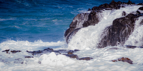 Sea foam covering dark rocks