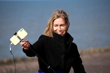 A young woman making a video using a selfie stick and microphone