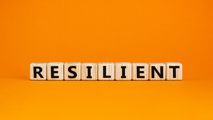 Resilient symbol. Wooden cubes with the word 'resilient'. Beautiful orange background. Business and resilient concept. Copy space.