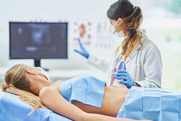 Doctor in mask doing ultrasound abdomen test to female patient