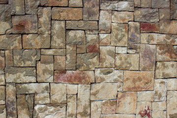 Wall of square stones of different sizes. Rectangular tiles of different sizes made of natural red stone