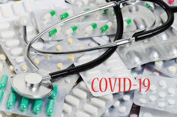 A pile of medical pills and capsules and a stethoscope