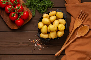 Young potatoes, raw, in a cast iron skillet, on a wooden background, top view, horizontal,