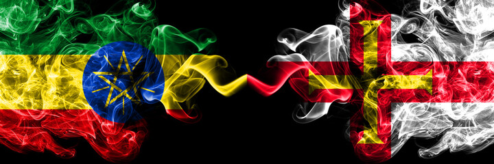Ethiopia, Ethiopian vs United Kingdom, Great Britain, British, Guernsey  smoky mystic flags placed side by side. Thick colored silky abstract smoke flags.