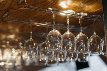 Fototapeta na wymiar Clean glasses for alcoholic beverages hang over the bar in a modern restaurant.