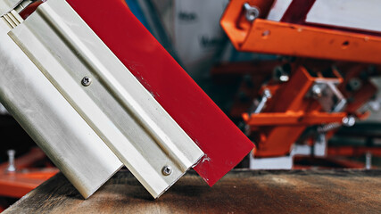 selective focus photo of a squeegee on wooden shelve of the print screening apparatus. serigraphy...