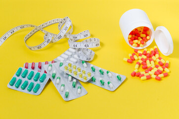 medical pills, measuring tape lie on a yellow background