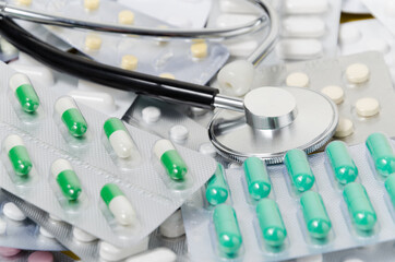 A pile of medical pills and capsules and a stethoscope