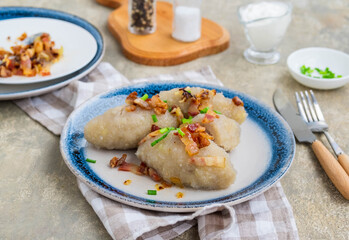 Traditional Lithuanian dish Zeppelin, boiled potato dumplings stuffed with minced pork, on a colored ceramic plate on a gray concrete background. © Natallya_ph