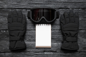 Snowboard tips or trick list mockup. Snowboard mask and gloves over black wooden table flat lay...