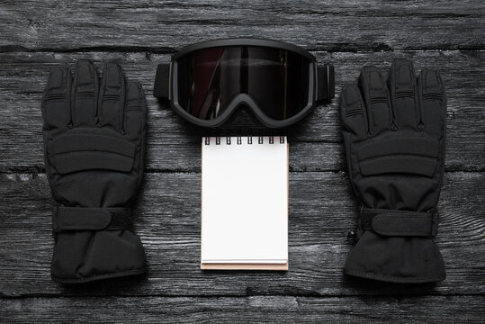 Snowboard tips or trick list mockup. Snowboard mask and gloves over black wooden table flat lay background. - Powered by Adobe