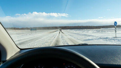 Snowy highway during strong wind. Truck goes on winter road. View of the road through the windshield of the car