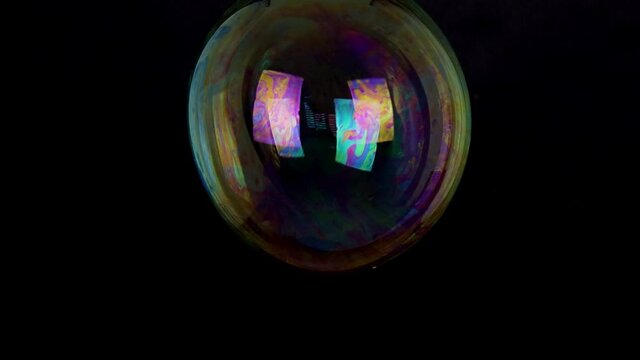 large soap bubble isolated on black background slow motion
