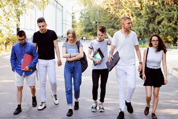 Confused and troubled students walking outdoors after the exam. Session time, friends with learning...