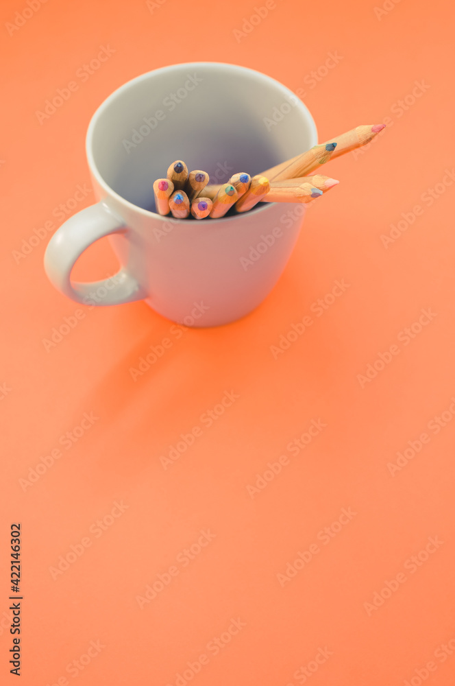 Canvas Prints Top view closeup of colored pencils put in a white mug on an orange background