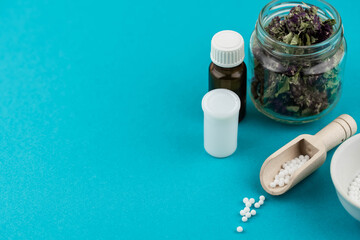 Homeopathy alternative medicine eco concept - classical homeopathy pills. Homeopathic globules and healing herbs. Blue background. 