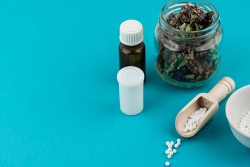 Homeopathy alternative medicine eco concept - classical homeopathy pills. Homeopathic globules and healing herbs. Blue background. 