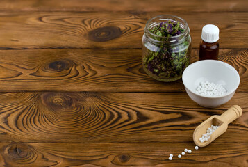 Obraz na płótnie Canvas Homeopathy alternative medicine eco concept - classical homeopathy pills. Homeopathic globules and healing herbs. Wooden background. 