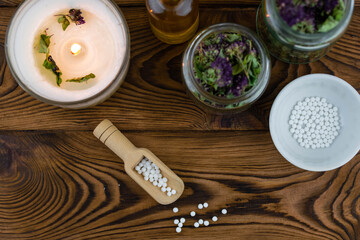 Homeopathy alternative medicine eco concept - classical homeopathy pills. Homeopathic globules, natural organic aroma oil essence and healing herbs. Wooden background. 