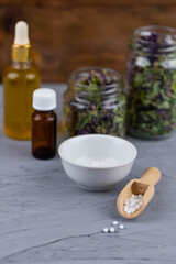 Homeopathy alternative medicine eco concept - classical homeopathy pills. Homeopathic globules, natural organic aroma oil essence and healing herbs. Wooden background. 